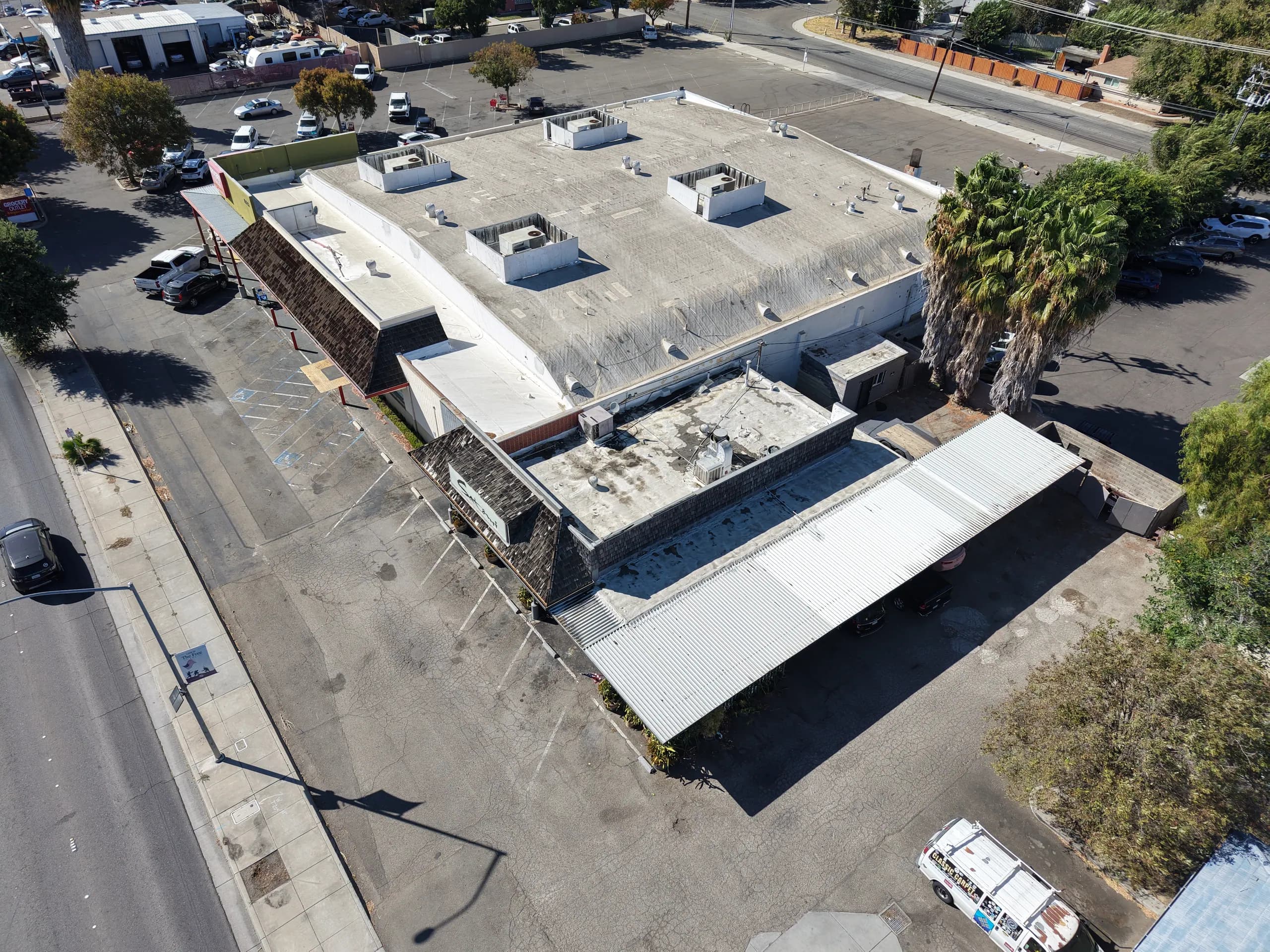 Angled drone view of a single-story retail center, its roofline and parking
