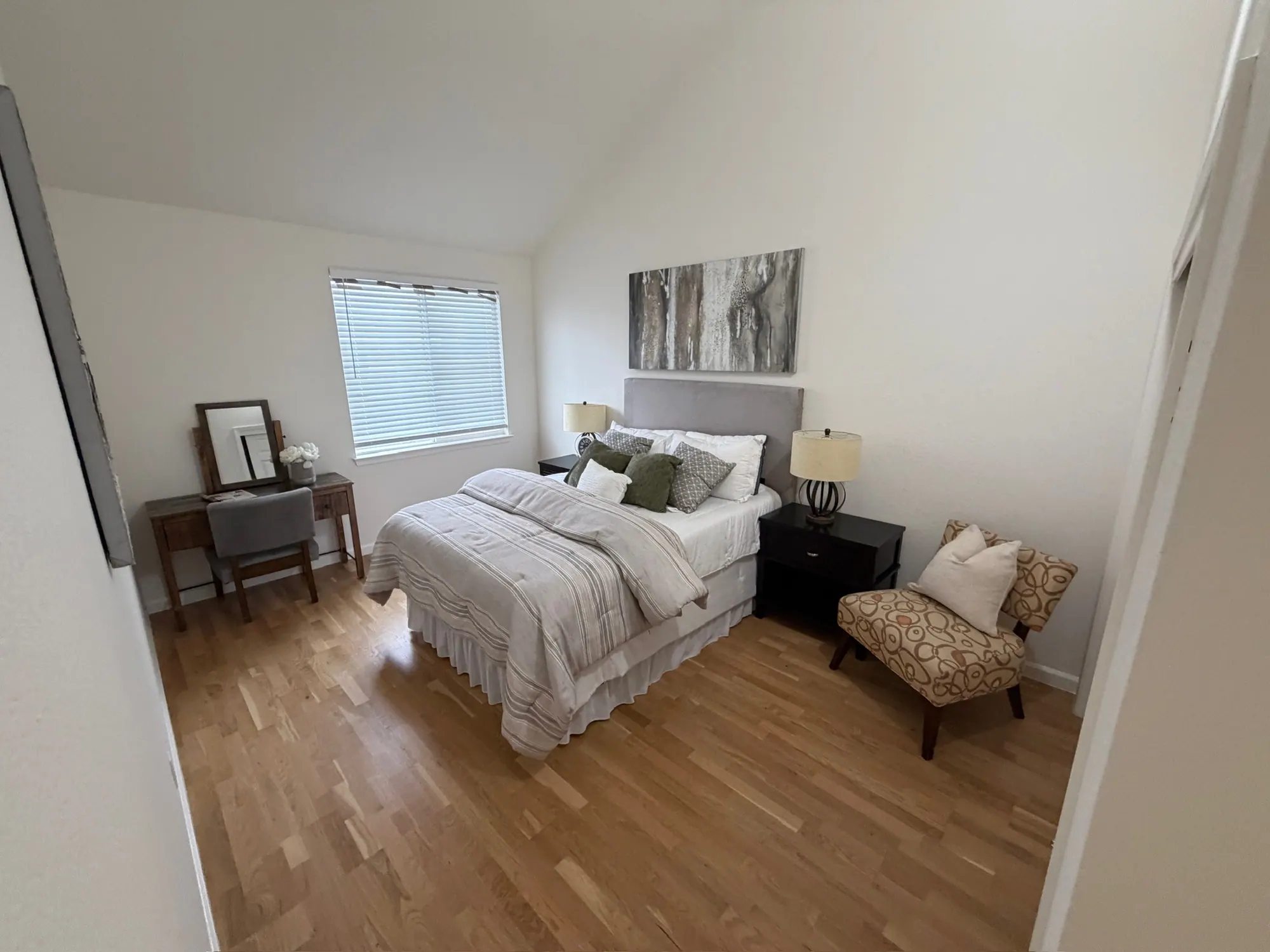 Staged bedroom with a vaulted ceiling and wood floors