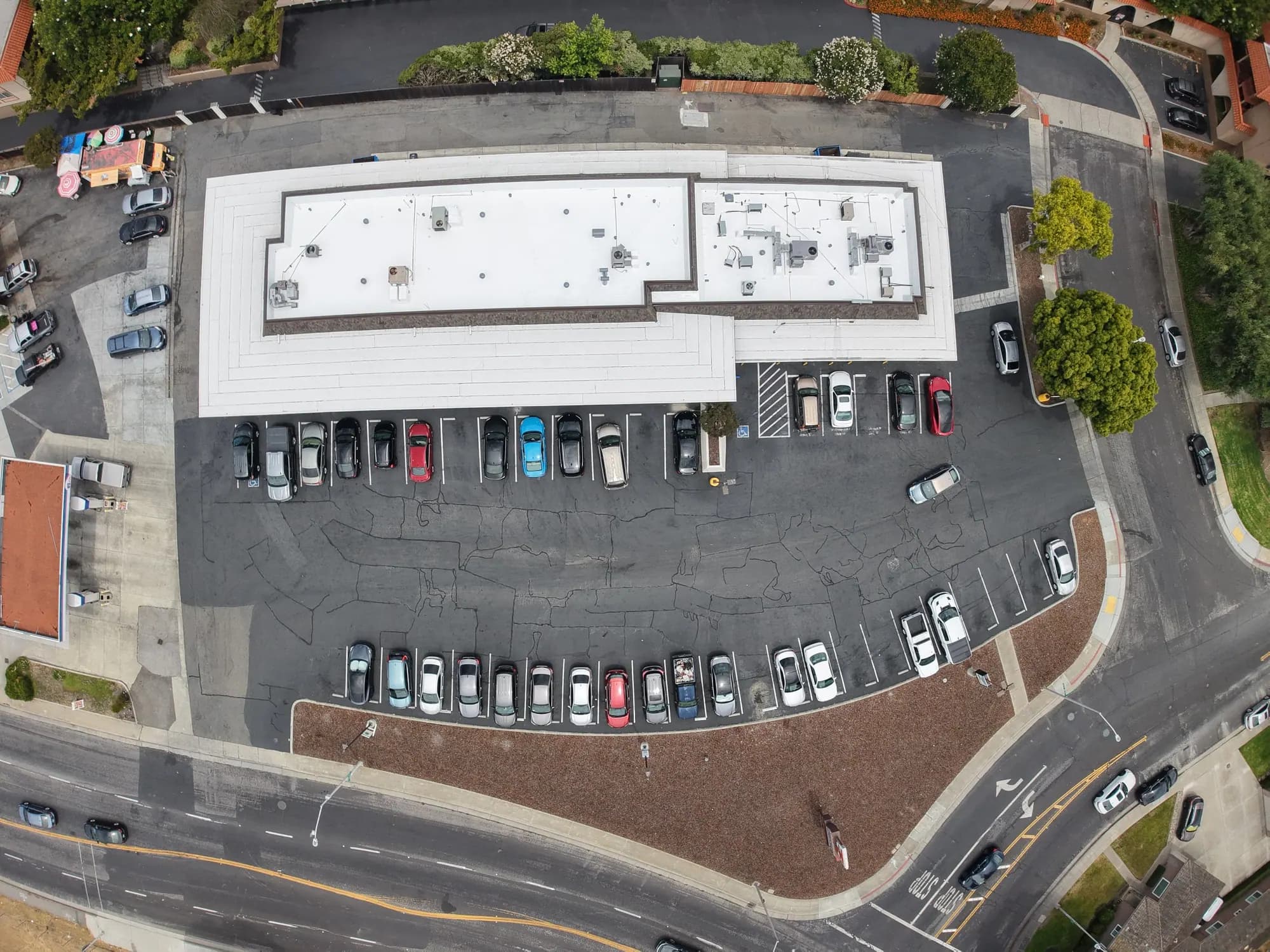 The strip center from above after recoating, its roof bright white