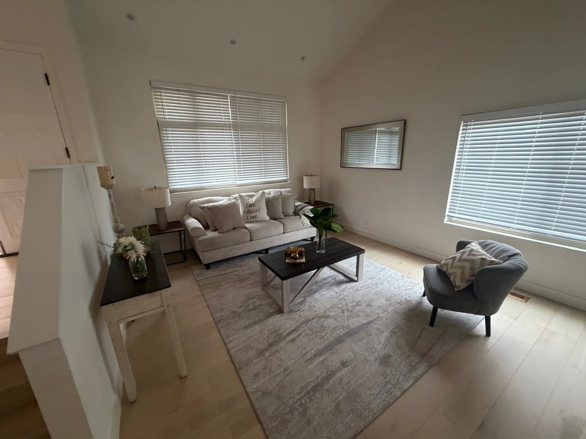 Staged living room with a white sofa, rug and vaulted ceiling