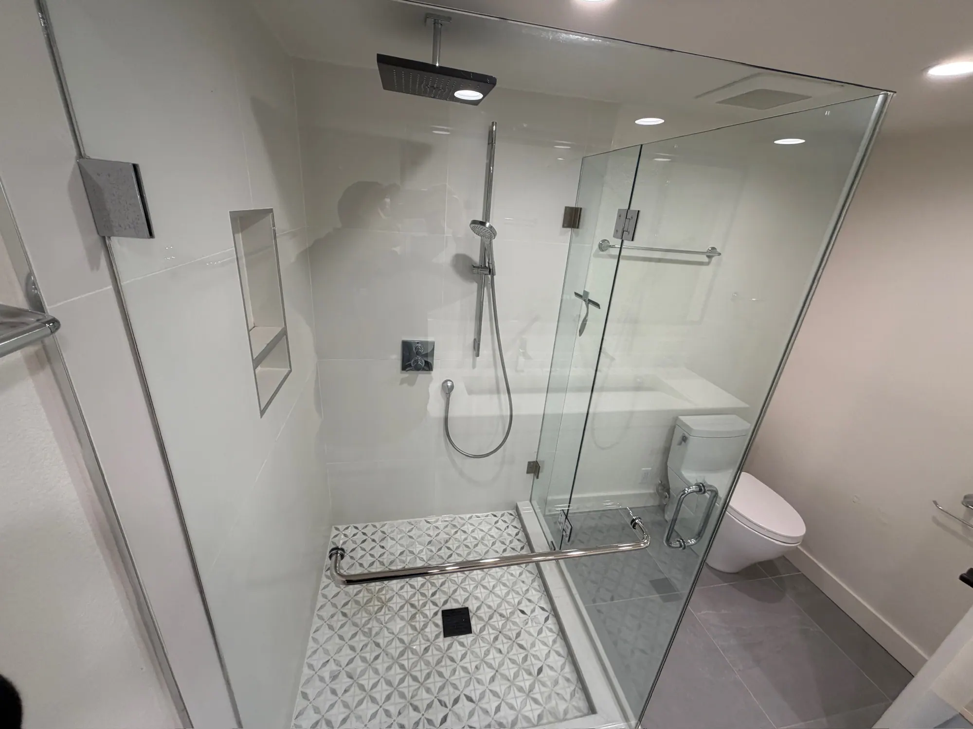 Frameless glass shower with a rain head and patterned floor tile