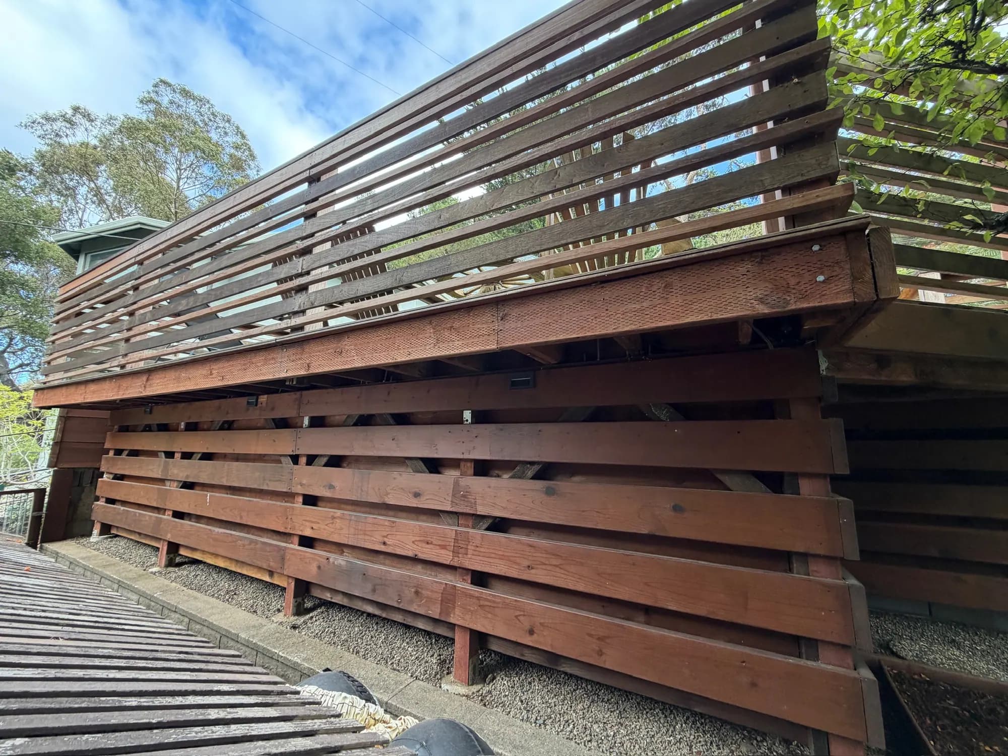 The pool deck from below: horizontal redwood slats over the engineered post-and-brace frame