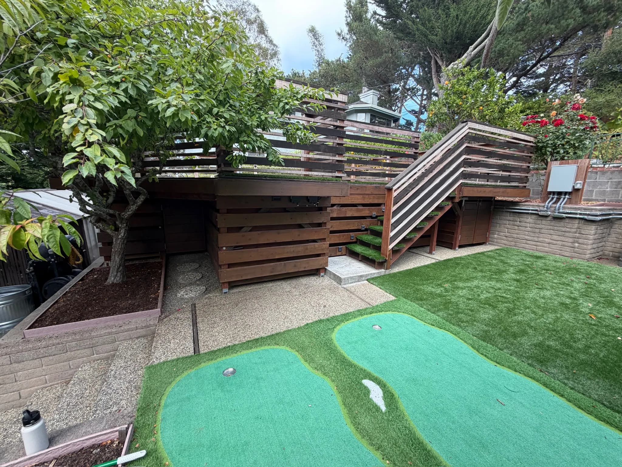 Terraced garden with a putting green, turf and the pool deck above