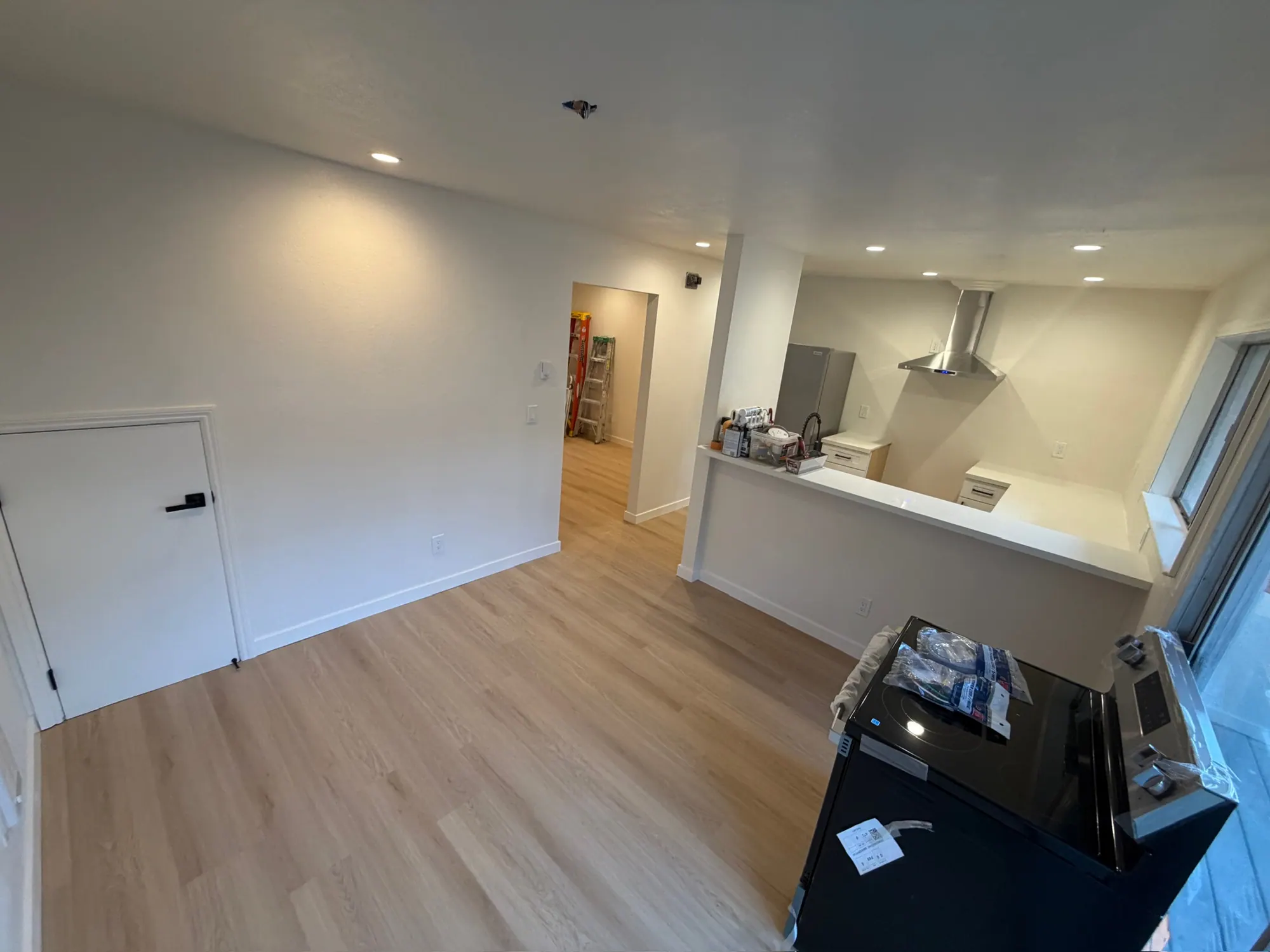 New kitchen with a peninsula, stainless range hood and plank floors