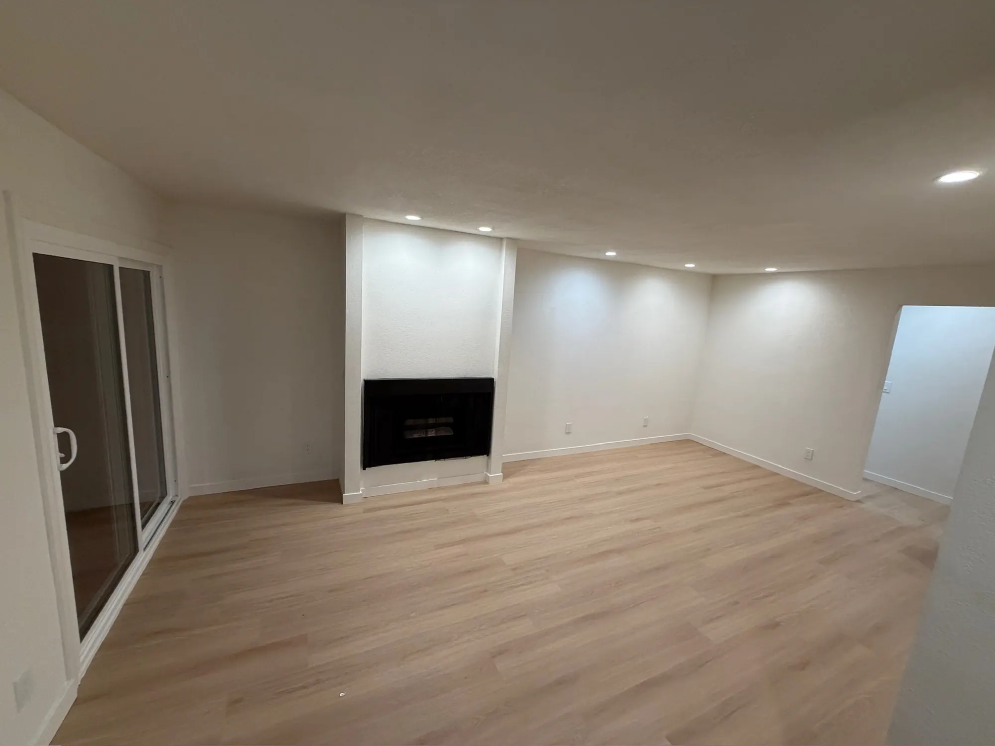 Renovated living room with a fireplace, sliding door and new plank flooring