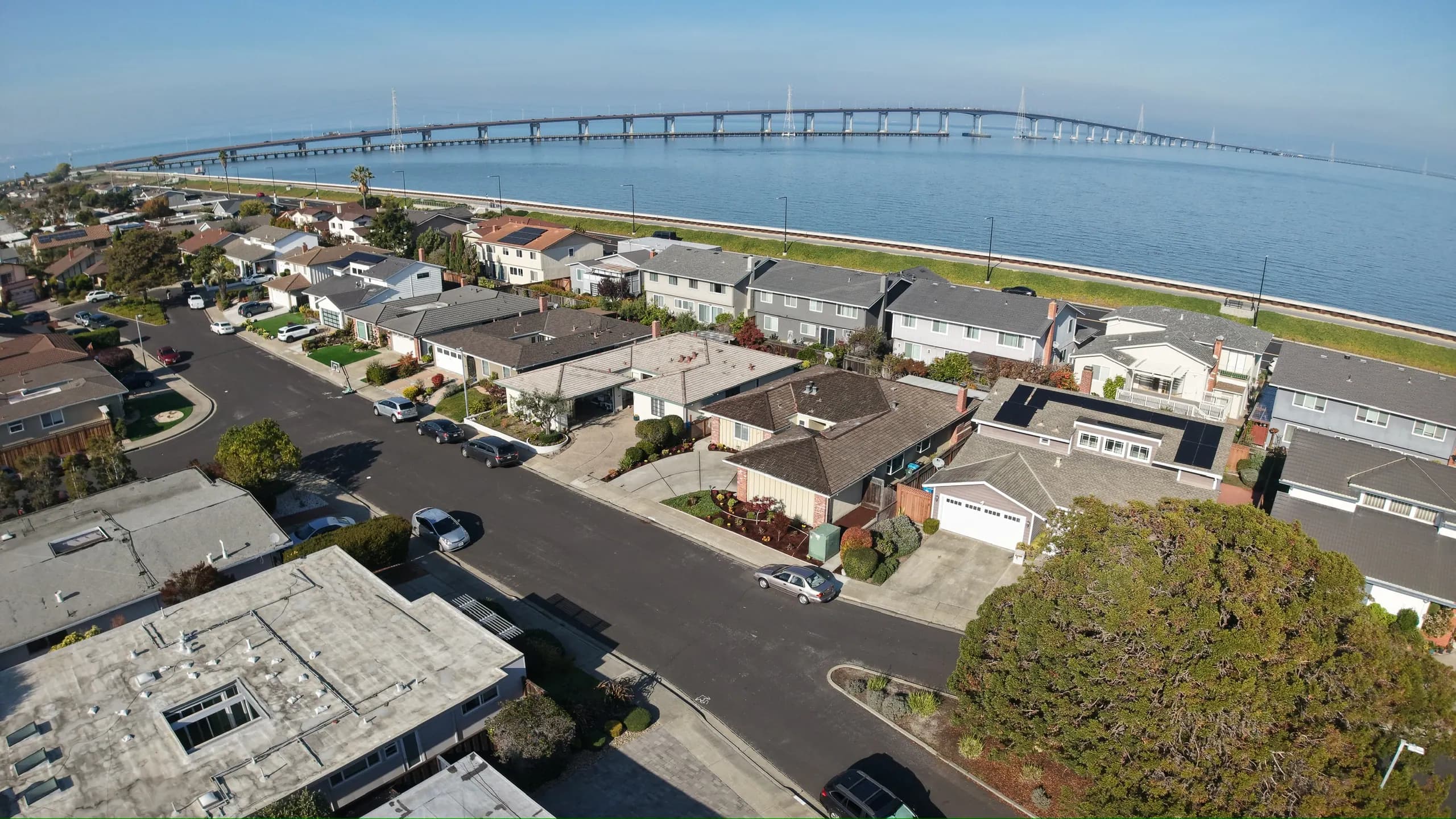 Drone view over the neighborhood toward the bay and a long bridge on the horizon