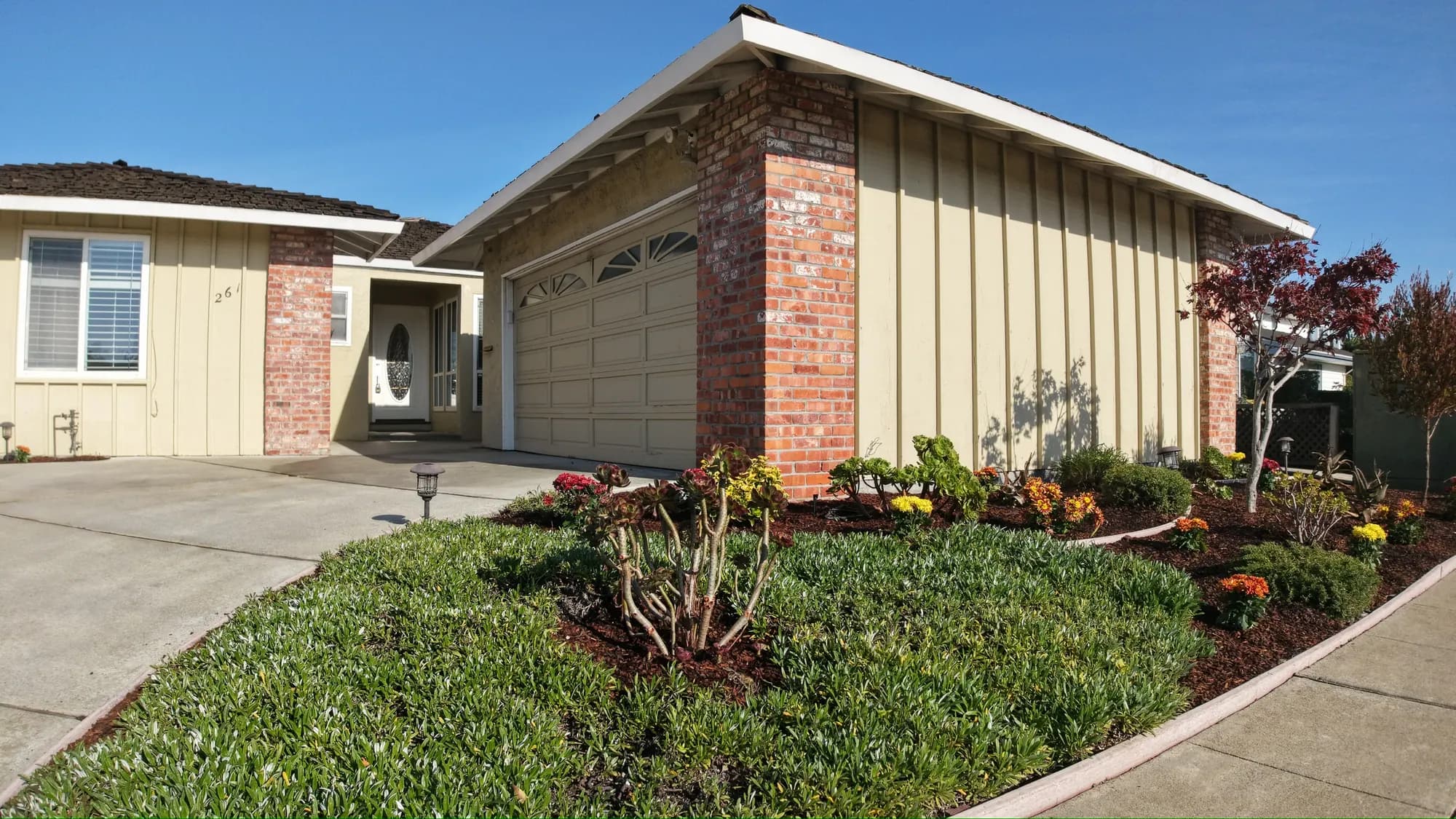 Front of a ranch home with a brick-faced garage and freshly planted flower beds