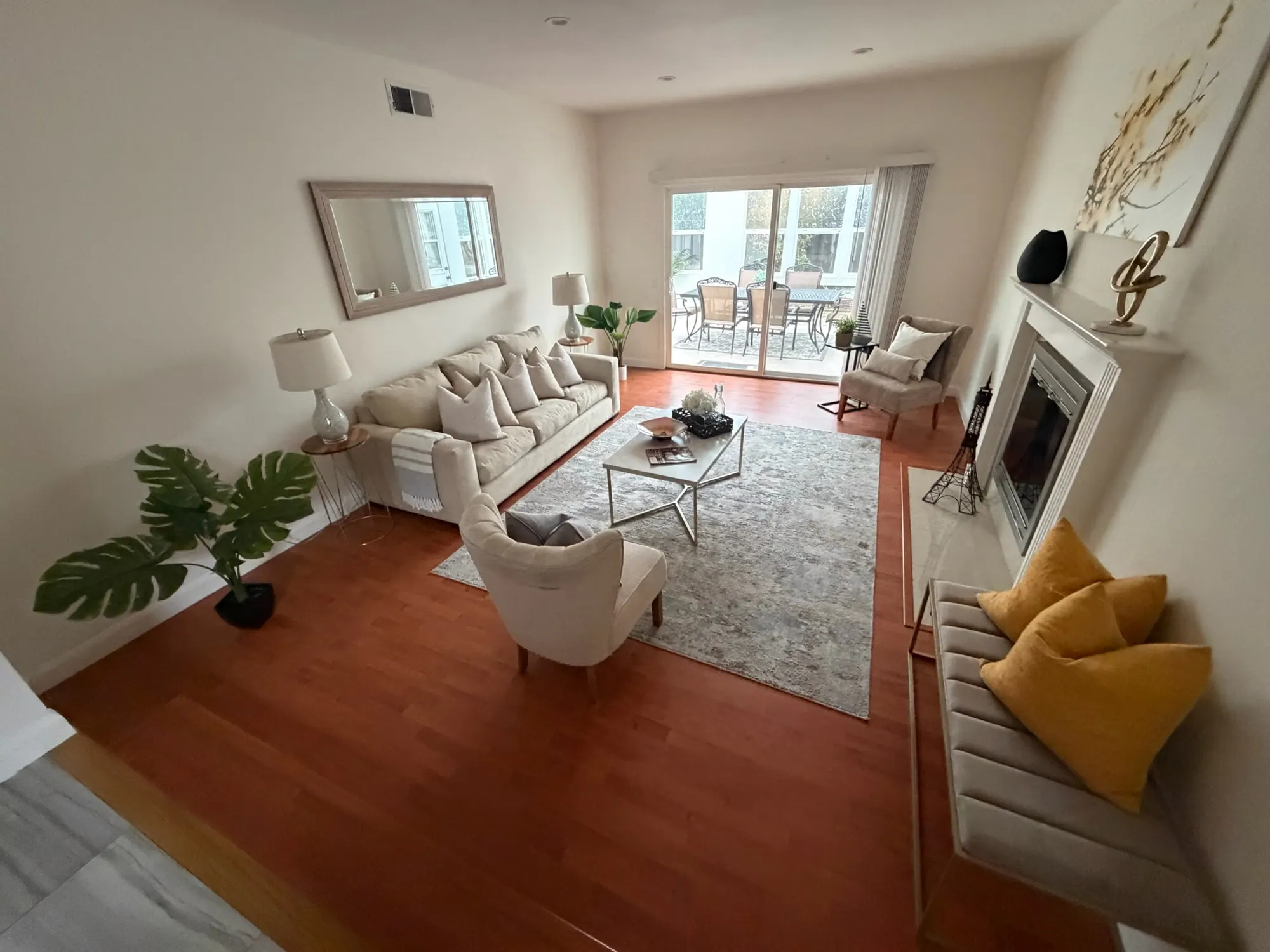 Staged living room with a fireplace, light sofa and hardwood floors