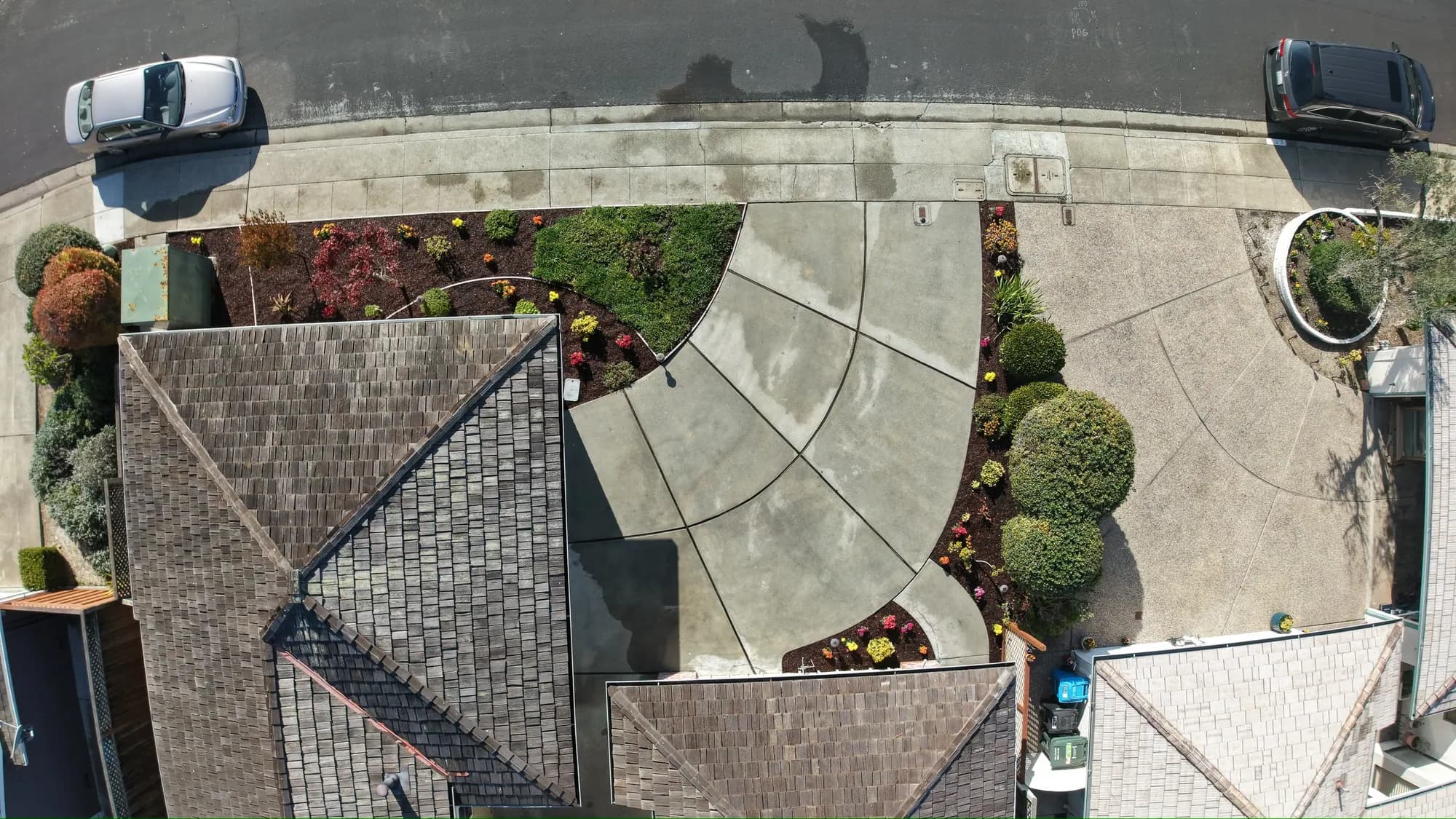 Straight-down drone view of a home’s front: new planting beds, a curved walkway and the driveway