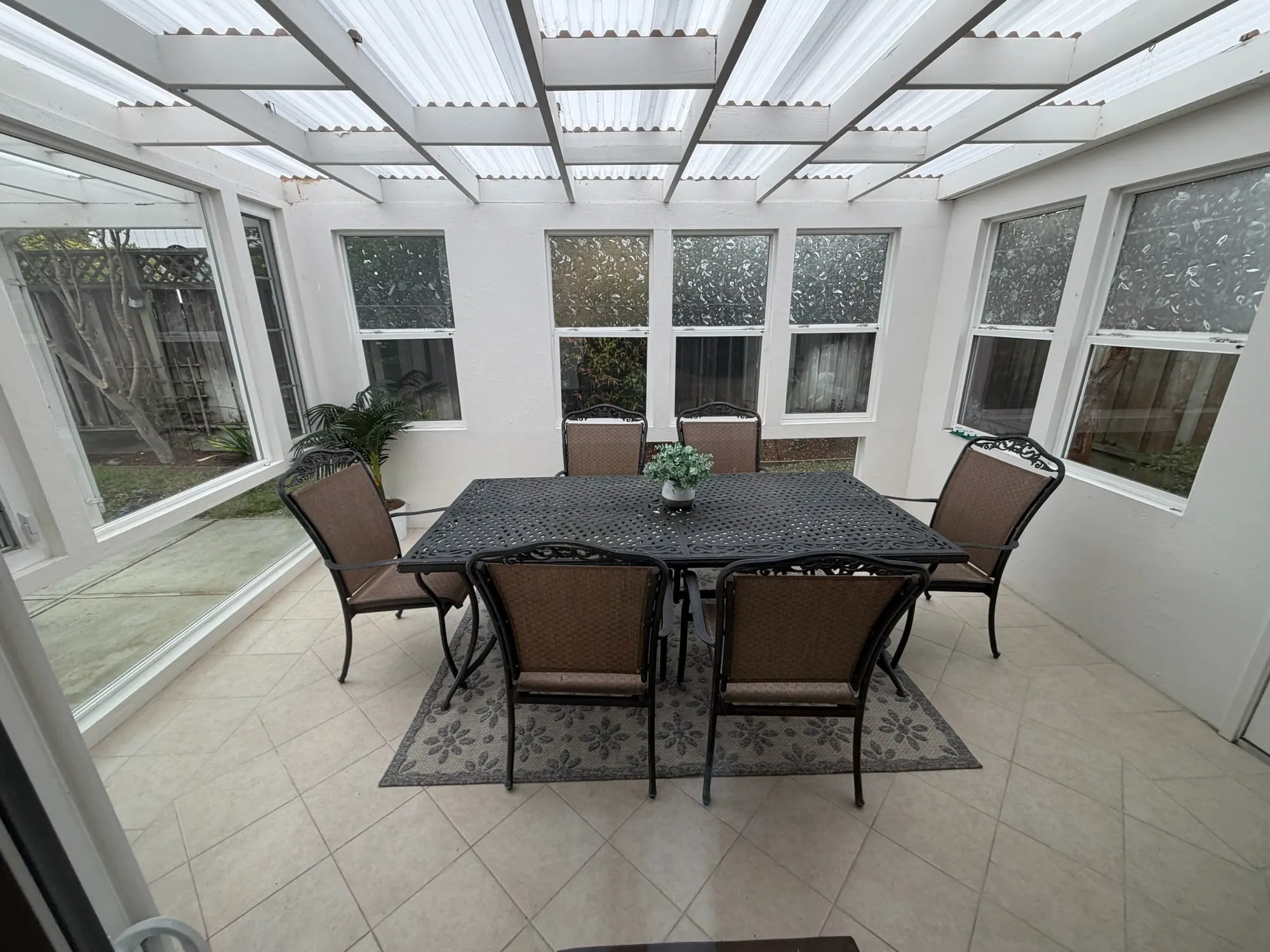 Finished sunroom with new translucent roof panels and a dining table set for showing