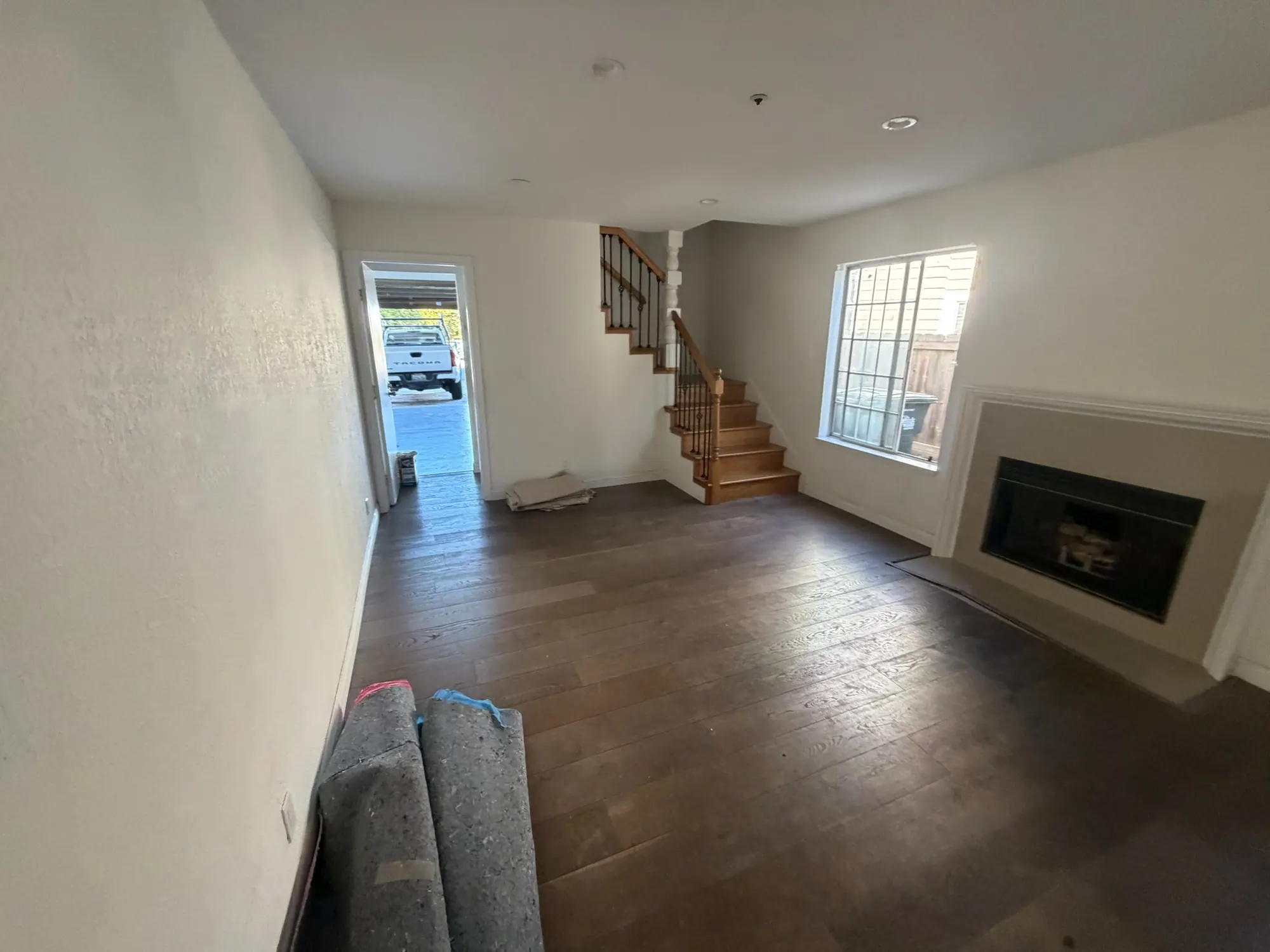 Living room with a fireplace, new wood floor and the staircase beyond