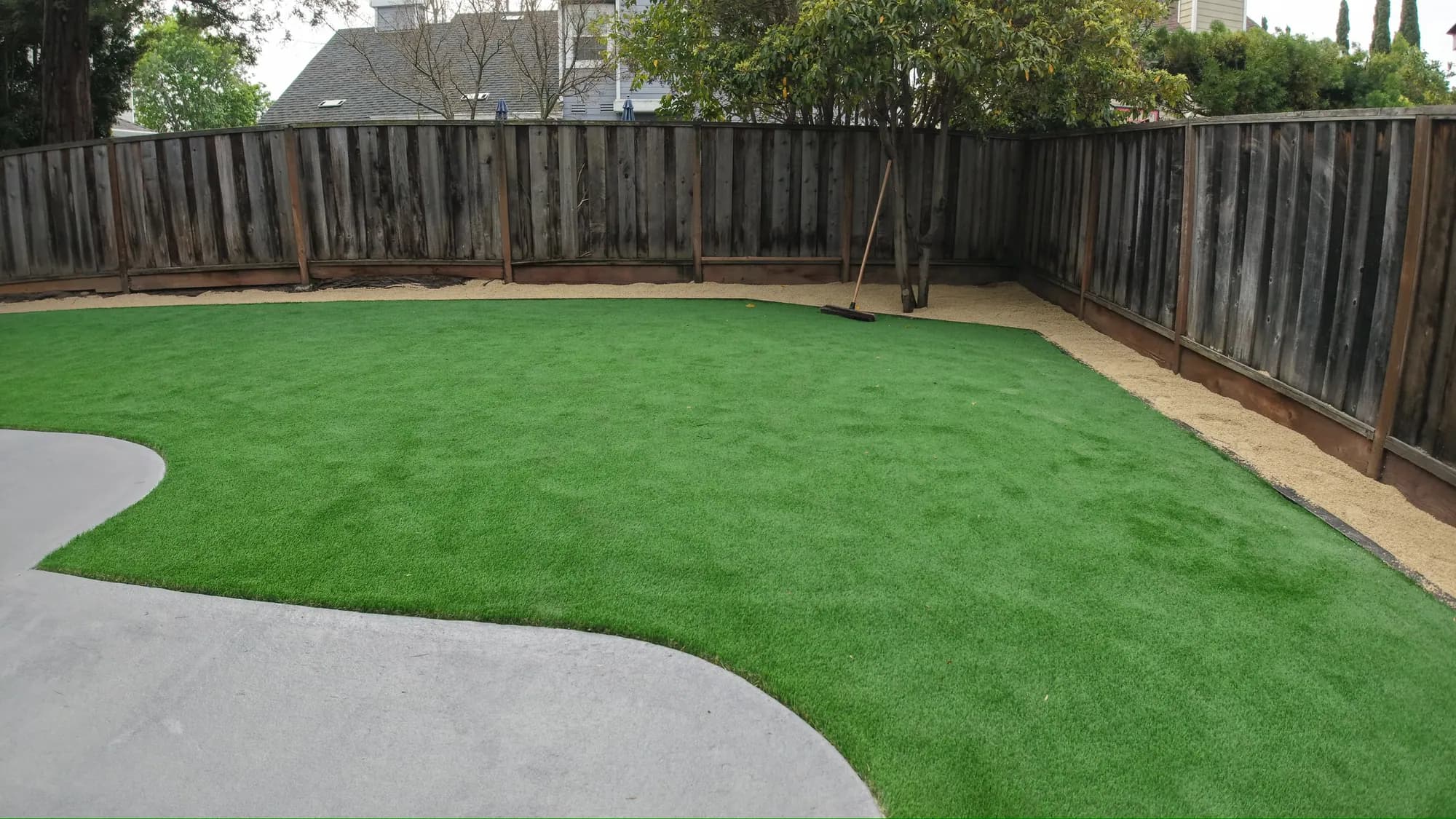 The finished backyard with artificial turf and a curved concrete path