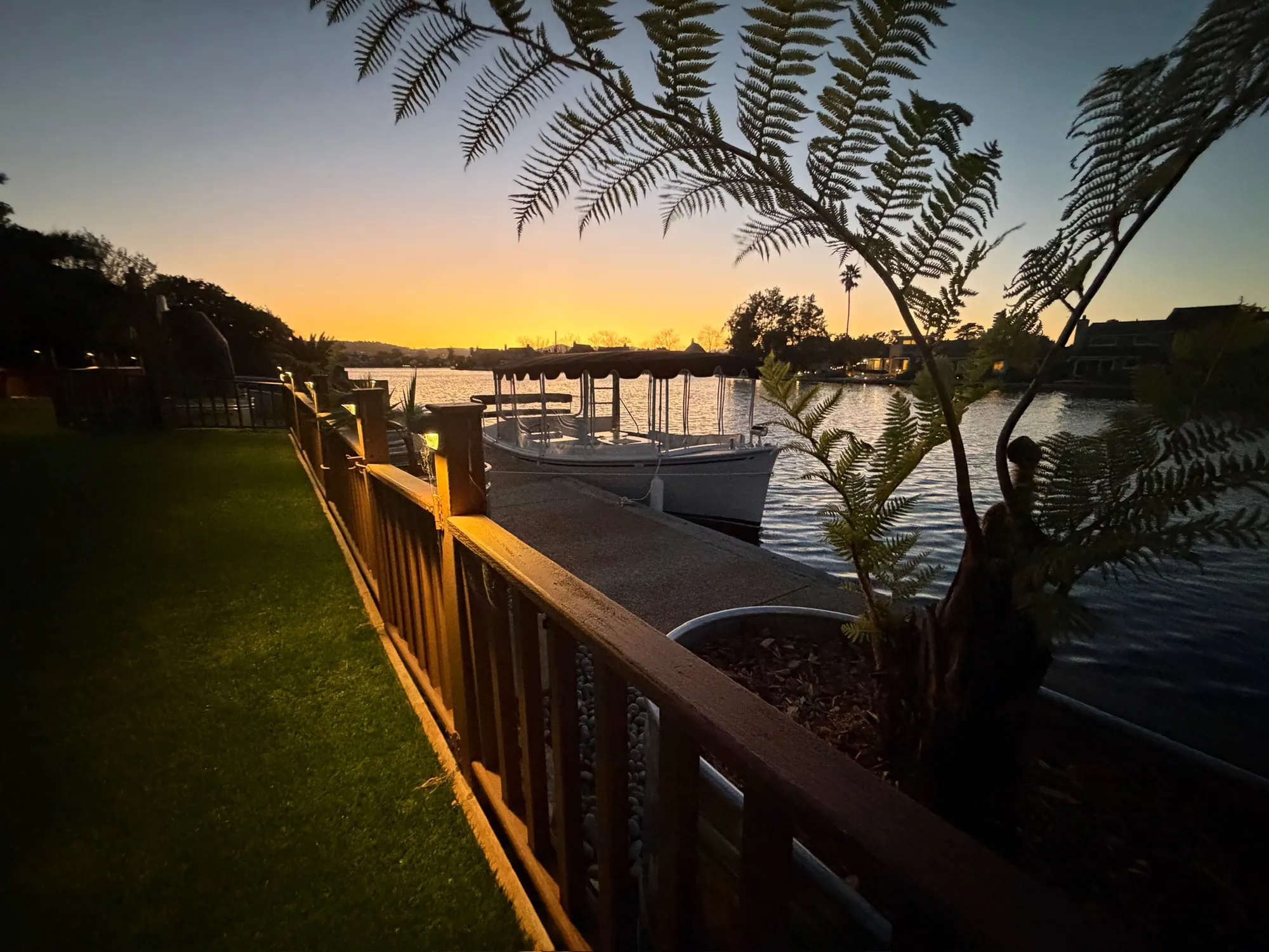 Lawn, railing and dock on the lagoon at dusk