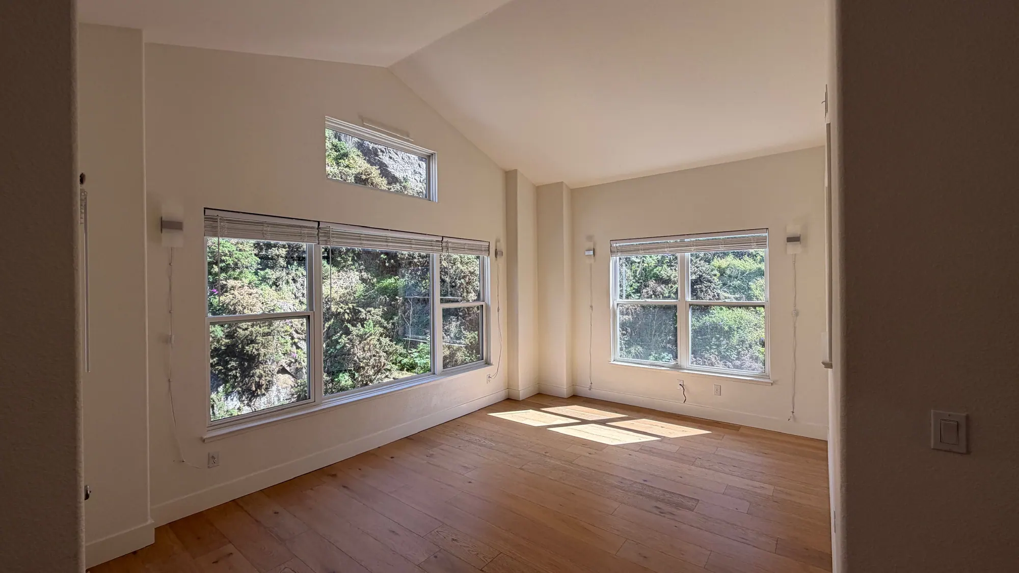 Bedroom with a vaulted ceiling, clerestory window and wood floor in afternoon light