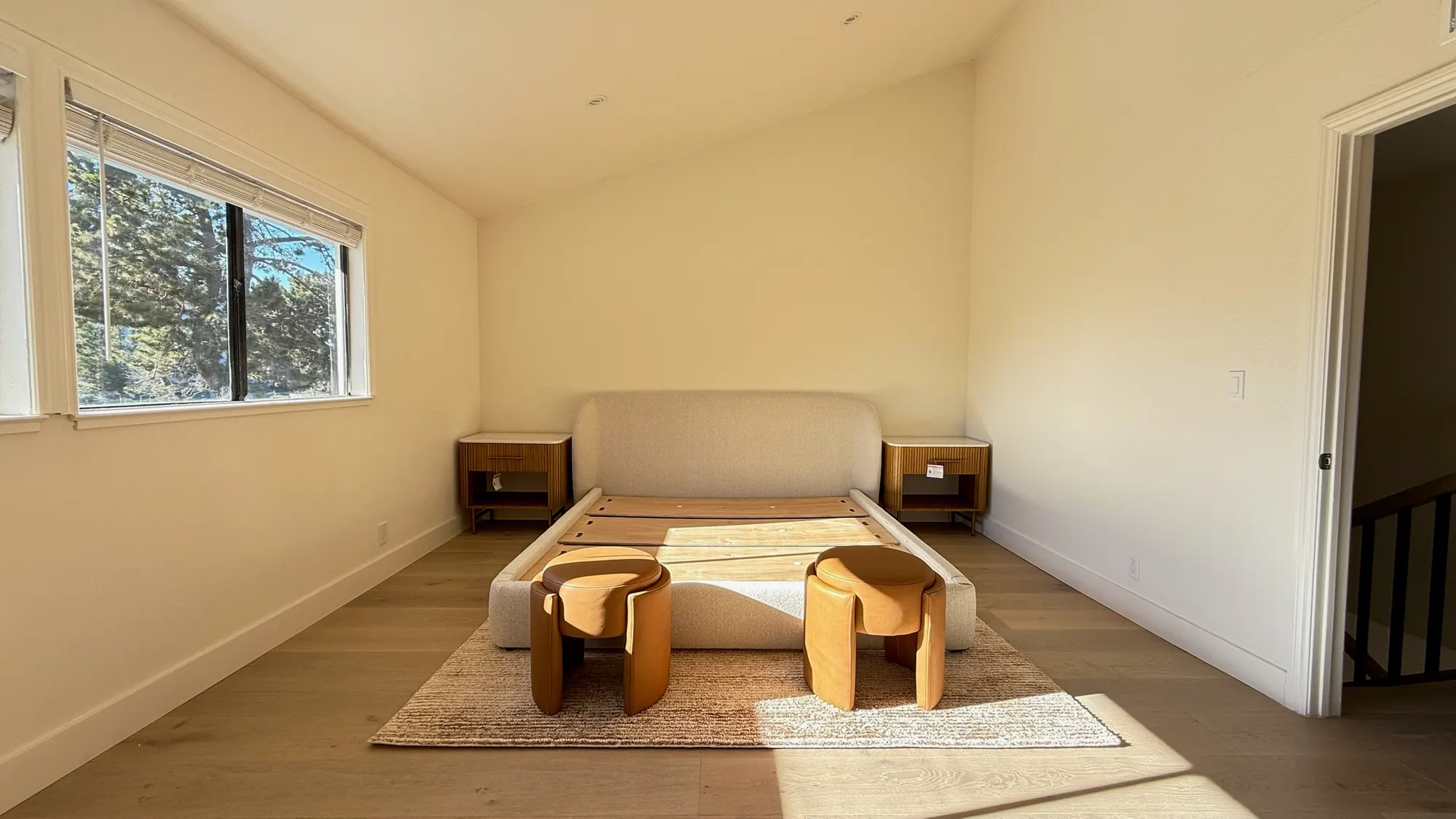 Sunlit bedroom with new floors and a low wooden bench