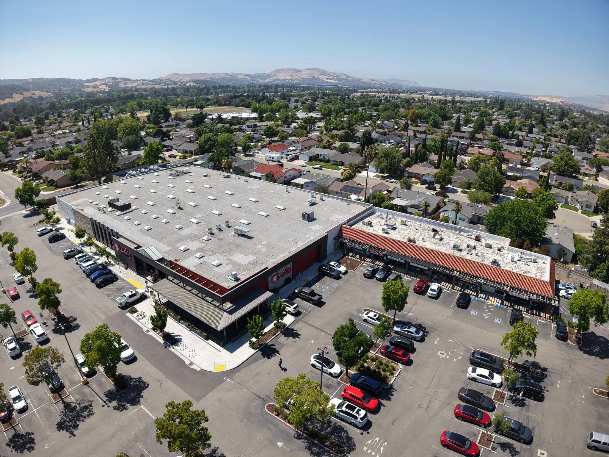 High aerial of the shopping center, its tile-roofed wing and the surrounding neighborhood