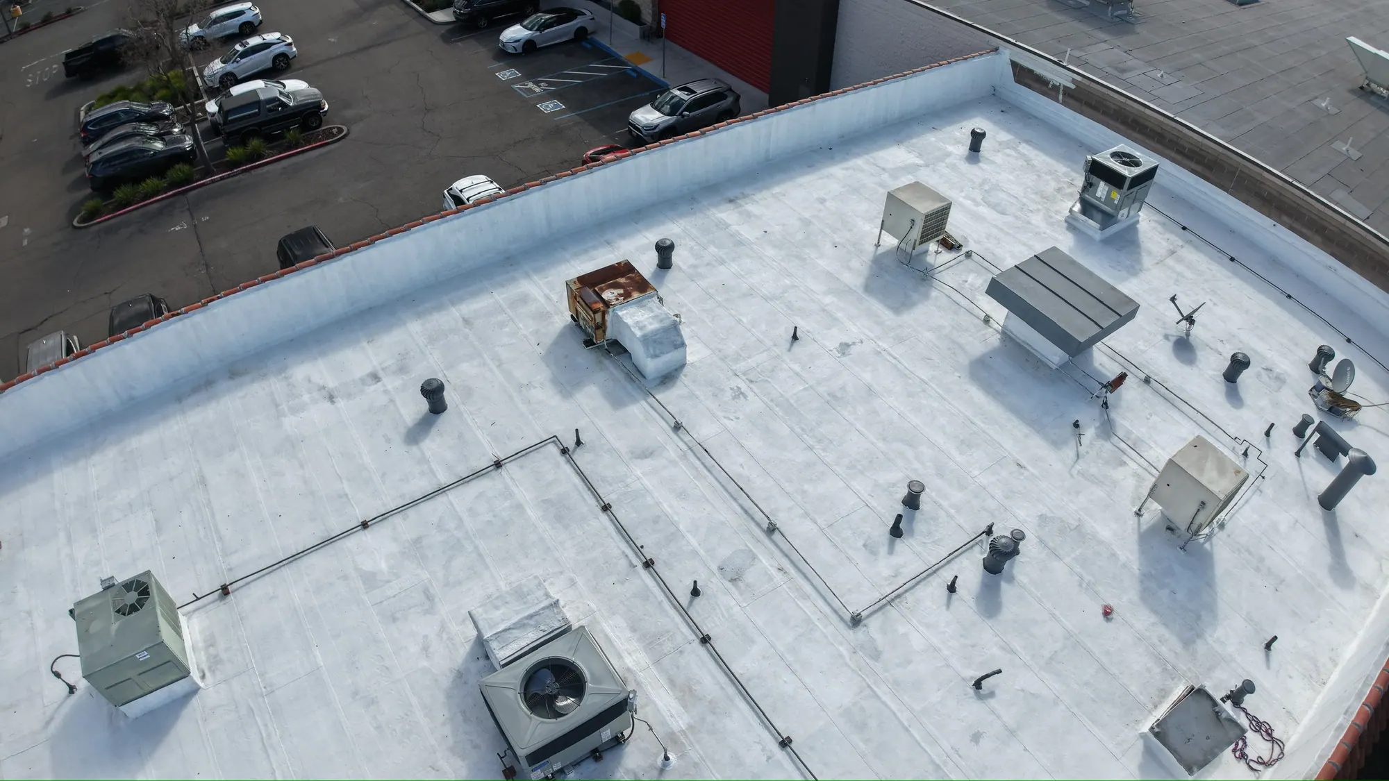 Rooftop HVAC units and conduit on a newly coated roof