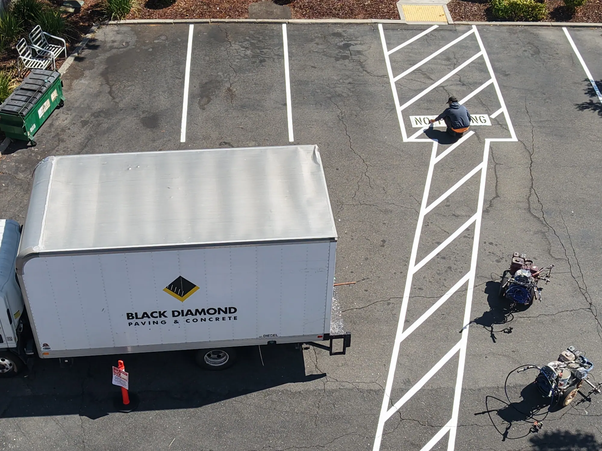 Fresh accessible-aisle striping going down in the parking lot, seen from above