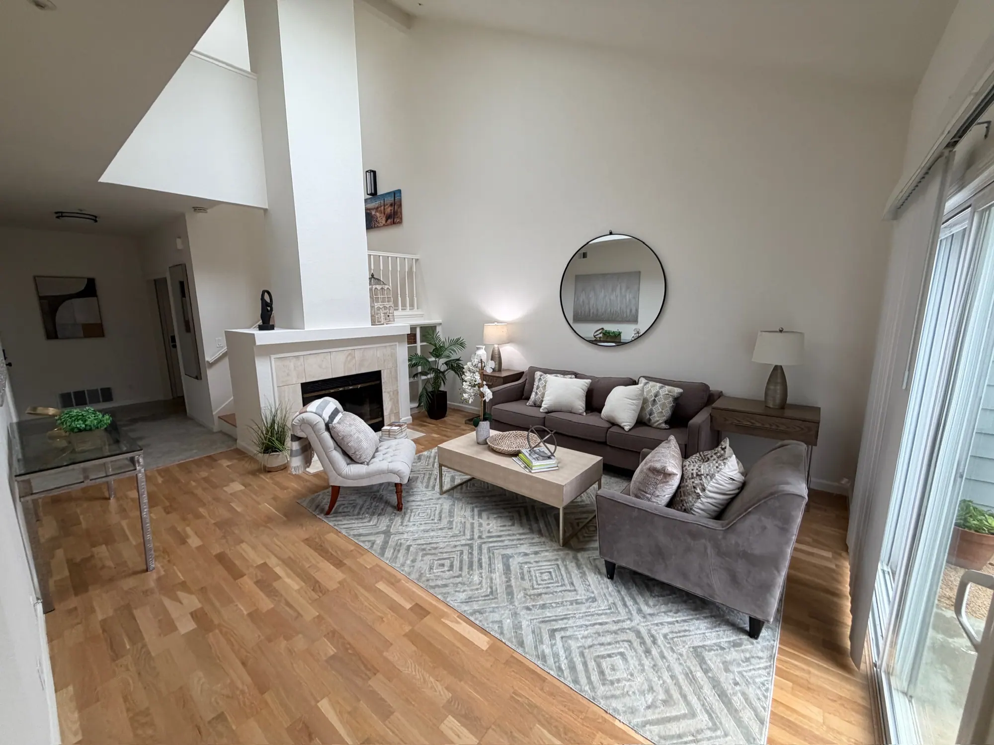 Staged living room with a fireplace, vaulted ceiling and wood floors